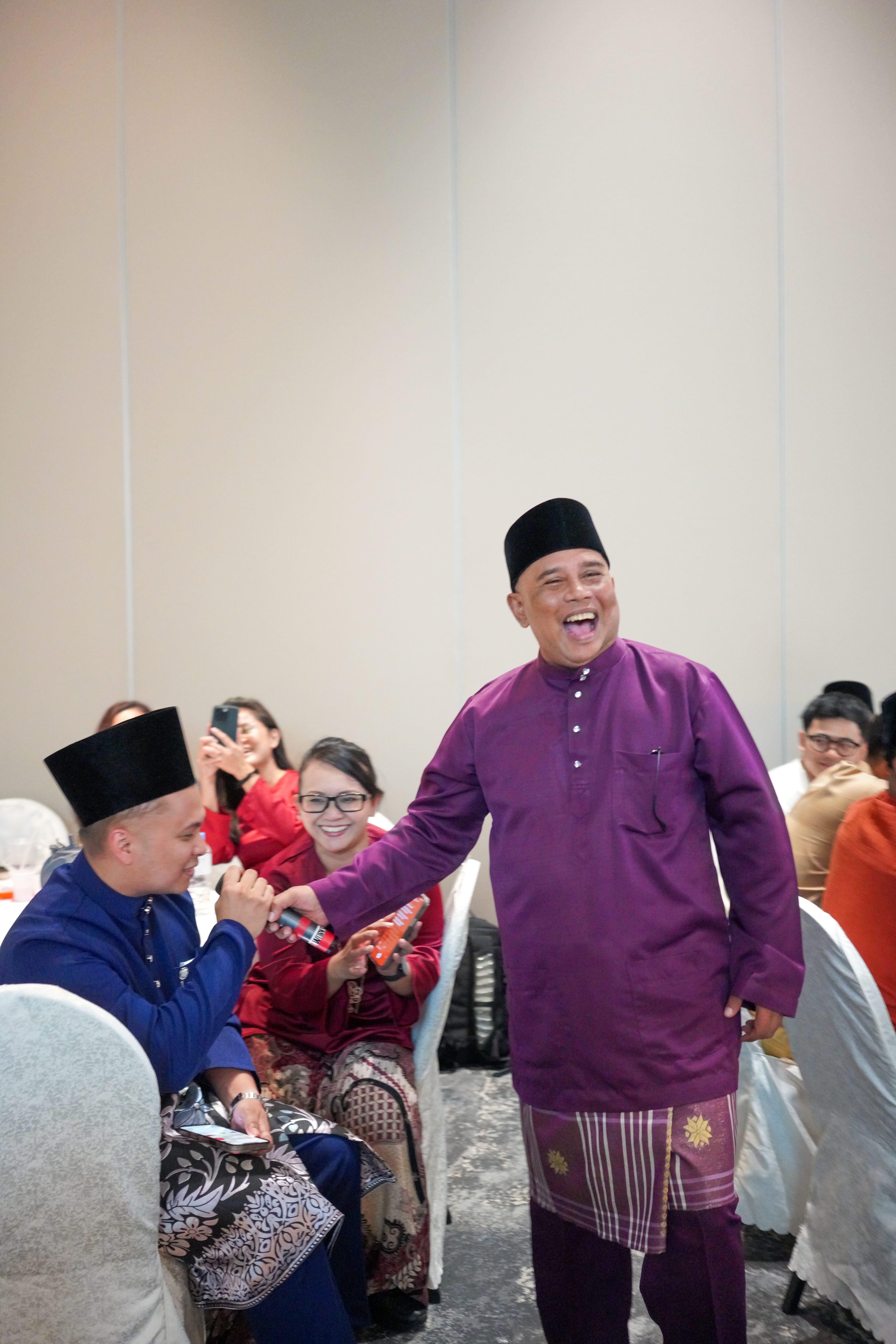 A participant laughing while taking part in an interactive entertainment segment among banquet tables.